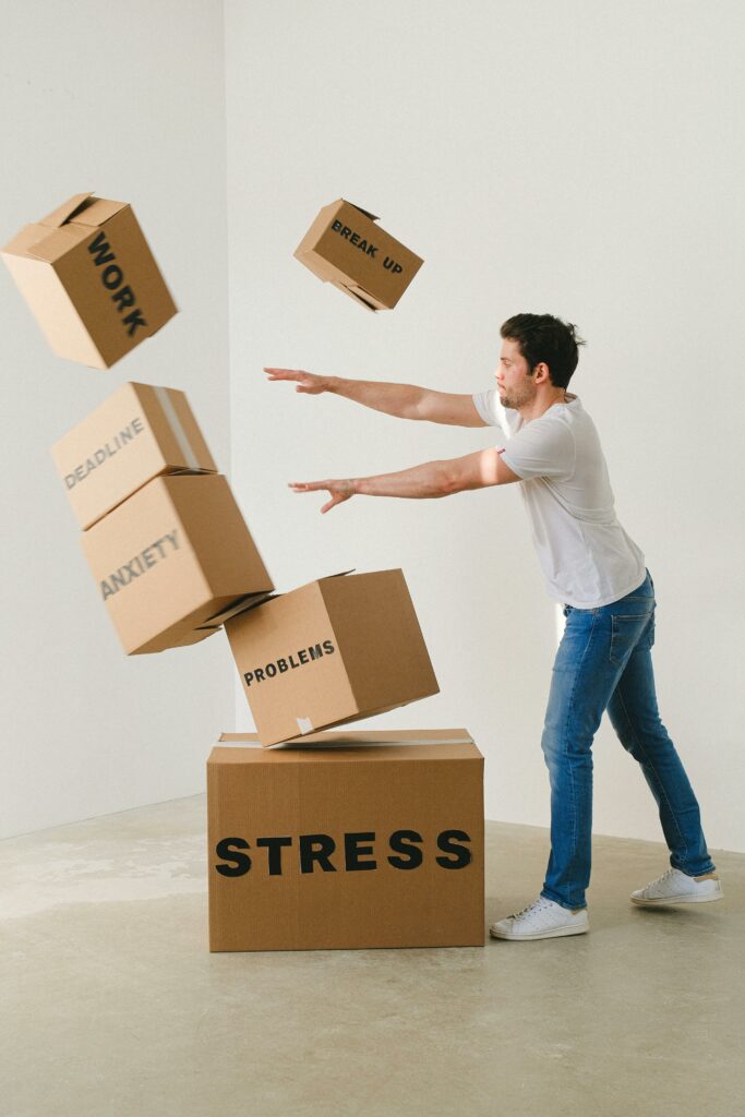 Full body of young man in sneakers and jeans pushing and falling boxes saying Work Problems Anxiety Stress and Deadline while fighting with problems