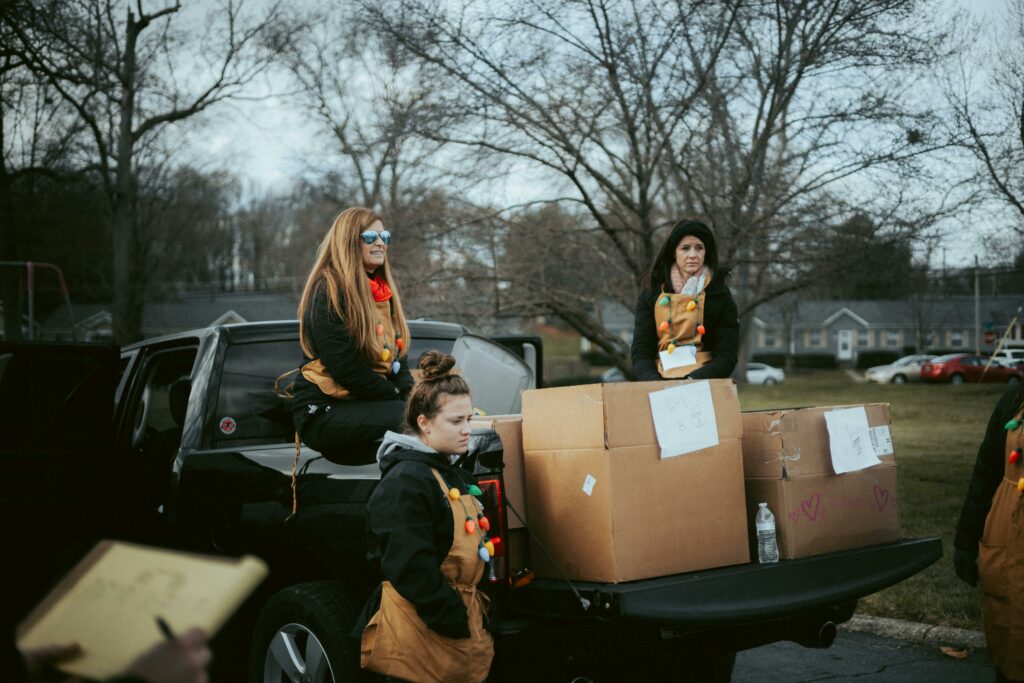 Volunteers in Christmas attire organizing gift delivery from a truck in a neighborhood.