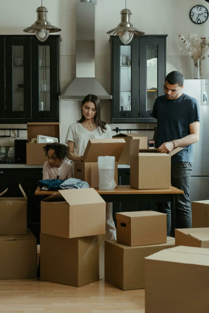 Family unpacking boxes together in a modern kitchen after moving into a new home.